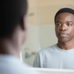 Man pausing to look at his reflection, thinking through the right questions before working on personal goal setting