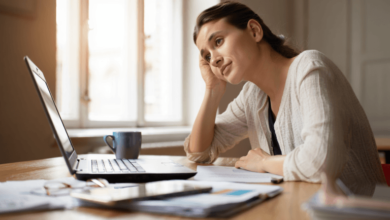 Woman at her desk with head in hand, too tired to focus — learning to stop feeling tired by managing energy not time